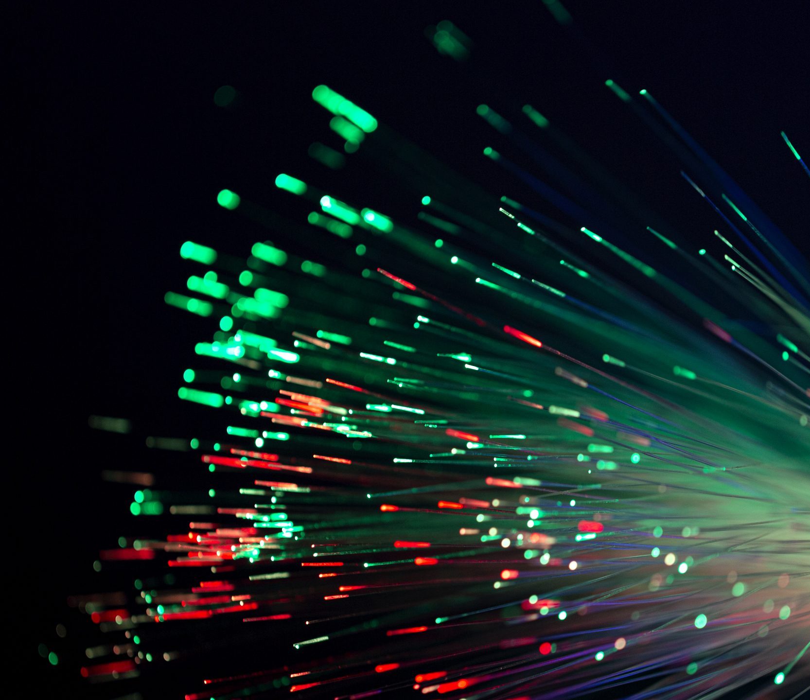 Bundle of optical fibers glowing green and red against a dark background, illustrating photonics applications.
