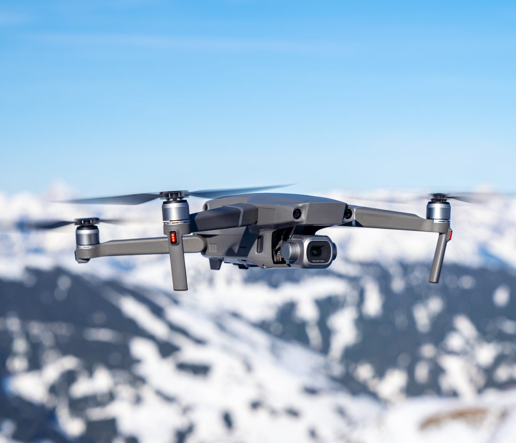 Quadcopter drone in flight above snow-covered mountains, used to carry gas measurement payloads.